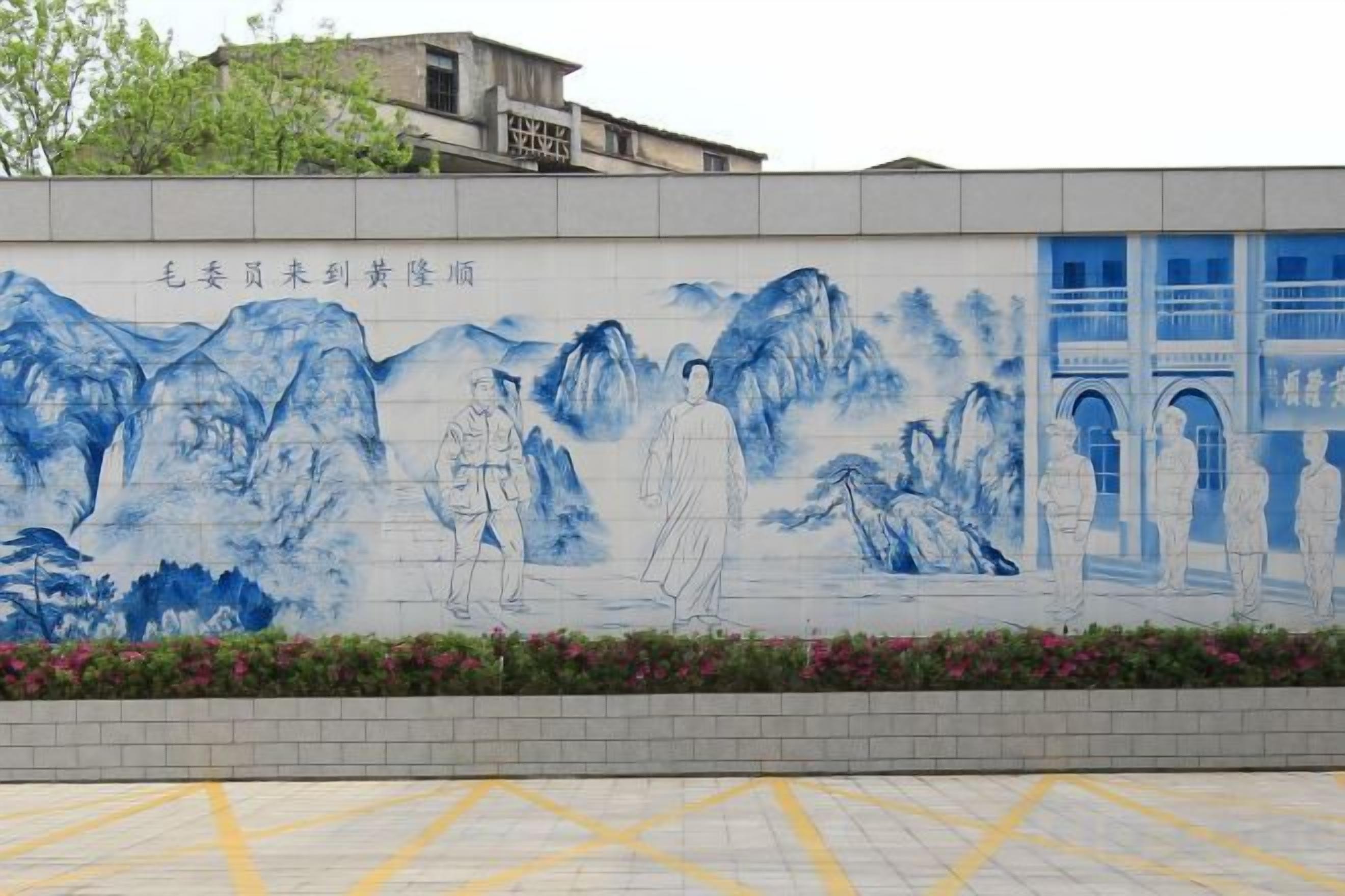 A mural with figures and mountains, a building with a sign, and a paved area with yellow lines.