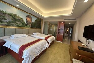Habitación de hotel con dos camas, televisión, escritorio y espejo.