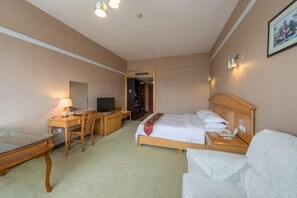 Une chambre d’hôtel comprenant un lit, un bureau, une chaise, une télévision et une lampe.
