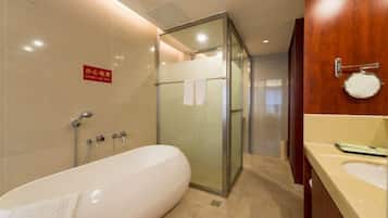 Un baño moderno con ducha envuelta en vidrio, una bañera grande y un tocador con espejo y lavabo.