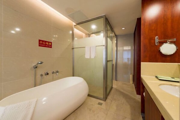 Une salle de bain moderne dotée d’une douche à parois de verre, d’une grande baignoire et d’un meuble-lavabo avec un miroir et un évier.