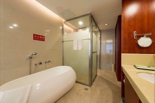 Un baño moderno con ducha envuelta en vidrio, una bañera grande y un tocador con espejo y lavabo.