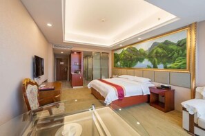 Une chambre d’hôtel moderne avec un grand lit, une table en verre, un téléviseur et un tableau représentant un paysage.