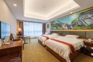 Une chambre d’hôtel avec deux lits, un bureau, une télévision et un tableau au mur.