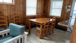 Ein Holzinterieur mit Esstisch, Stühlen, einer Couch und einer Küchenzeile.
