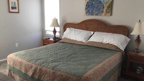 A bedroom with a bed, a nightstand, a lamp, a painting, and a window. - 4 bedroom accommodation in Barnegat Light (Barnegat Light)