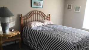 A bedroom with a wooden bed, a bedside table with a lamp, and a wall with framed pictures. - 4 bedroom accommodation in Barnegat Light (Barnegat Light)