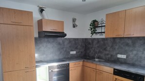 Een moderne keuken met houten kastjes, een ingebouwde oven en een vaatwasser.