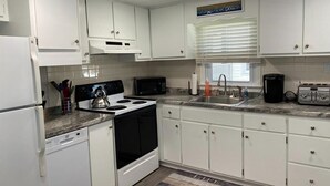 A kitchen with white cabinets, a stove, a microwave, and a toaster. - Ocean block duplex located in the heart of Surf City. (Surf City)