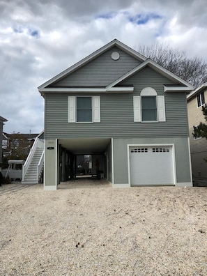 A two-story house with a garage, a covered driveway, and a staircase leading to the entrance.