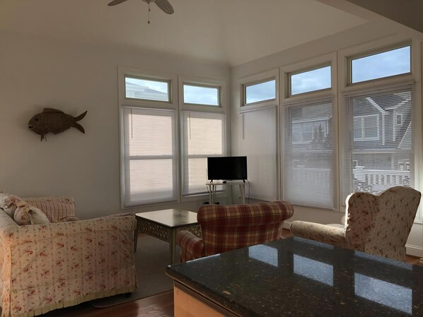 A room with a large window, a fish decoration, a television, and a dining table.