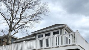 A two-story house with a covered patio area, a deck, and a large tree in the background. - 3 BEDROOM IN DESIRABLE BEACH HAVEN (Beach Haven)