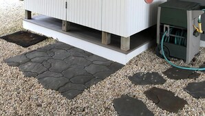 A white outdoor storage unit with a hinged door, a small step leading up to it, and a hose connected to a green pump on the right. - 3 BEDROOM IN DESIRABLE BEACH HAVEN (Beach Haven)