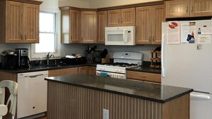 A kitchen with wooden cabinets, a central island, a microwave, a refrigerator, and pendant lighting. - 3 BEDROOM IN DESIRABLE BEACH HAVEN (Beach Haven)