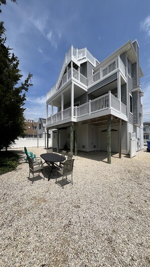 Un bâtiment à deux étages doté d’un balcon, d’un espace extérieur aménagé pour s’asseoir et d’un sol recouvert de gravier.