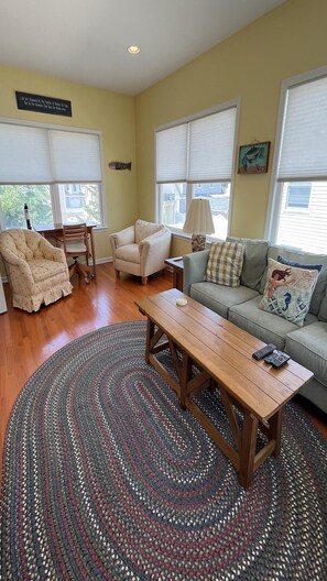 Un salon avec une table basse en bois, un canapé, deux fauteuils et un tapis à motifs.
