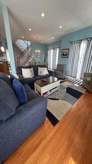 A living room with a sofa, a coffee table, and a chair. There is a staircase leading to an upper level.