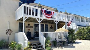 A two-story building with a porch, a welcome sign, and American flags. - LBI vacation rental property (Holgate)