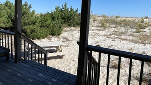 A wooden deck with a view of a sandy beach and sparse vegetation. - OCEANFRONT 1st Floor Duplex (Beach Haven)