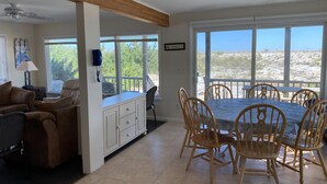 A spacious living area with a dining table, chairs, a sofa, and a view of the outdoors. - OCEANFRONT 1st Floor Duplex (Beach Haven)
