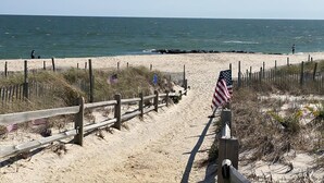 A sandy beach with wooden fences and American flags.