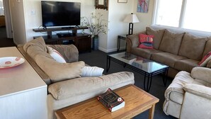 A living room with a sofa, a coffee table, a TV, and a bookshelf.