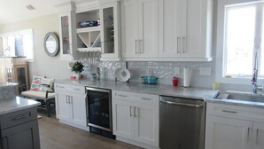 Een moderne keuken met witte kastjes, roestvrijstalen apparatuur en een groot raam voor natuurlijk licht.