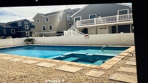 Ein rechteckiger Pool mit Fliesenbordierung, umgeben von einer Kiesfläche.