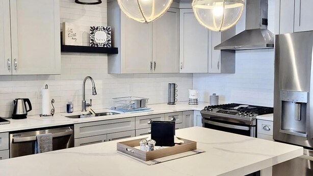 A modern kitchen with a large island, stainless steel appliances, and pendant lighting. - Ocean view vacation rental on LBI (Ship Bottom)
