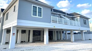 A two-story building with a covered porch, multiple doors, and a balcony. - Ocean view vacation rental on LBI (Ship Bottom)