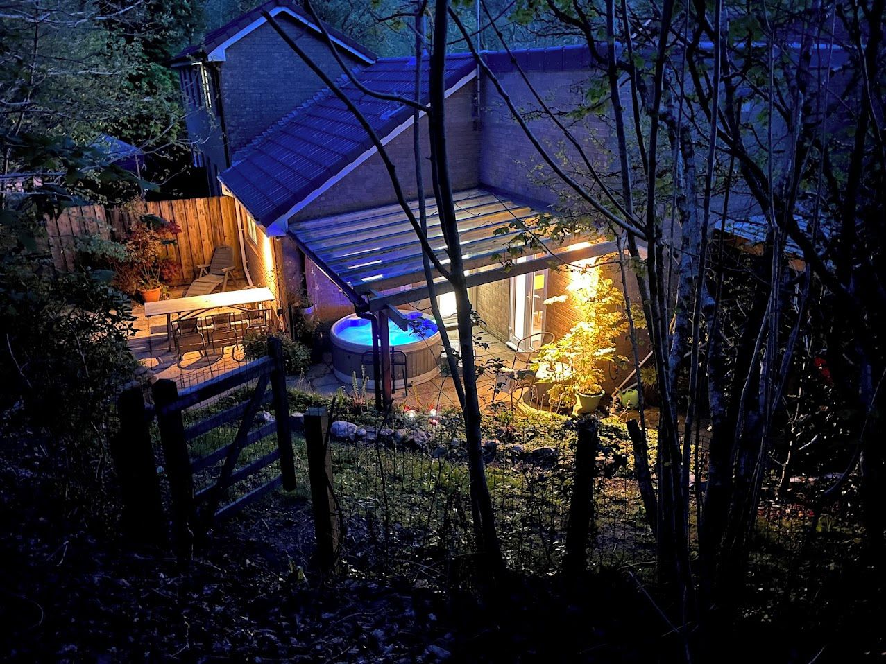 Una casa amb una zona exterior coberta, una banyera hidromassatge i una tanca de fusta.