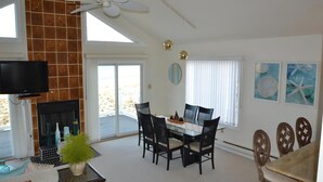 A dining area with a table and chairs, a fireplace, a ceiling fan, and a TV mounted on the wall. - Ocean Front Single Family Home located in Beach Haven Gardens (Beach Haven Gardens)