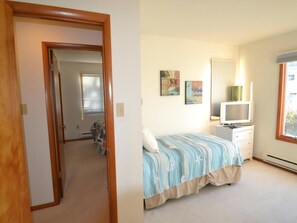Une chambre à coucher avec un lit, une télévision, une commode et une fenêtre.