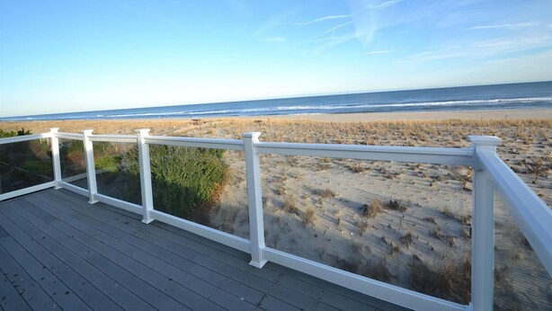 A wooden deck with white railings overlooking a beach. - Ocean Front Single Family Home located in Beach Haven Gardens (Beach Haven Gardens)
