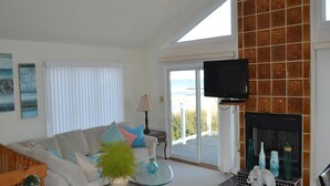 A living room with a sofa, a coffee table with a plant, a television, and a fireplace. - Ocean Front Single Family Home located in Beach Haven Gardens (Beach Haven Gardens)