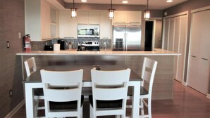 Una cocina moderna con una isla central, sillas blancas e iluminación colgante.