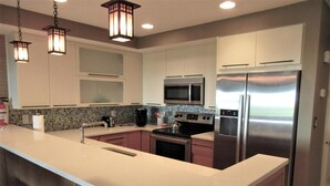 Una cocina moderna con una isla central, electrodomésticos de acero inoxidable e iluminación colgante.