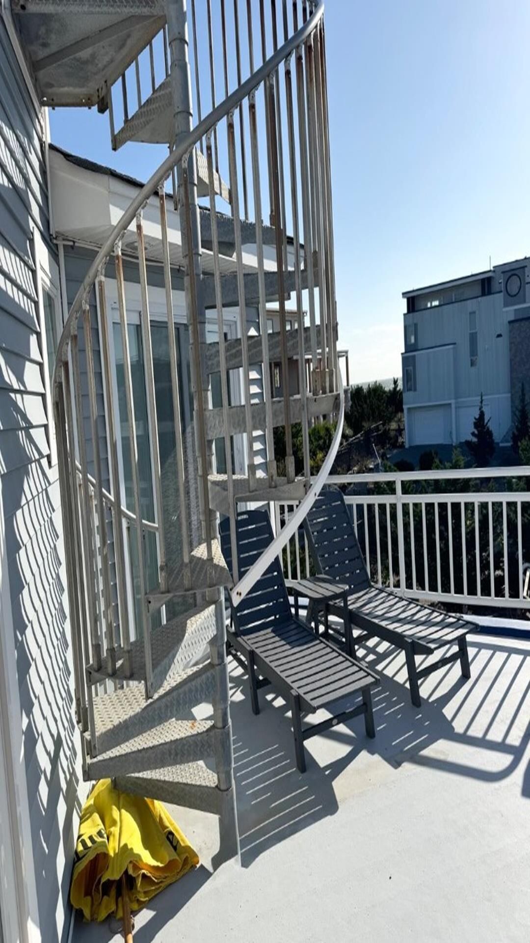 A spiral staircase leading to a balcony with outdoor seating.