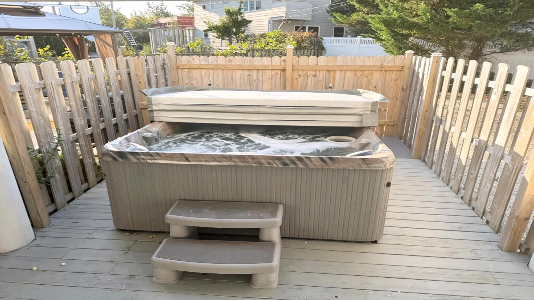 A hot tub with a wooden deck and a small step stool in front.