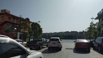 A parking area with several cars, a body of water, and buildings in the background.