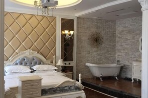 A bedroom with a large bed, a bathtub, and a mirror. - Impression Theme Hotel (Nan County)