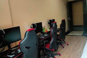 A room with gaming chairs, multiple monitors, and a gaming desk.