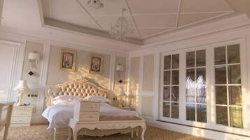 A bedroom with a large bed, a chandelier, and a view through a window.