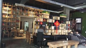 A cozy indoor space with wooden furniture, bookshelves, and a black sofa. - Impression Theme Hotel (Nan County)
