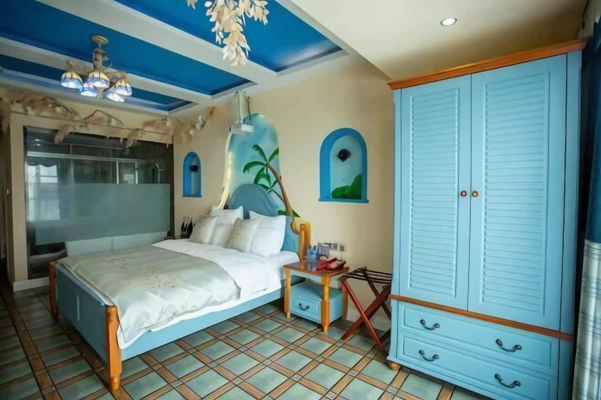 A bedroom with a bed, a wardrobe, a nightstand, and a mirror.