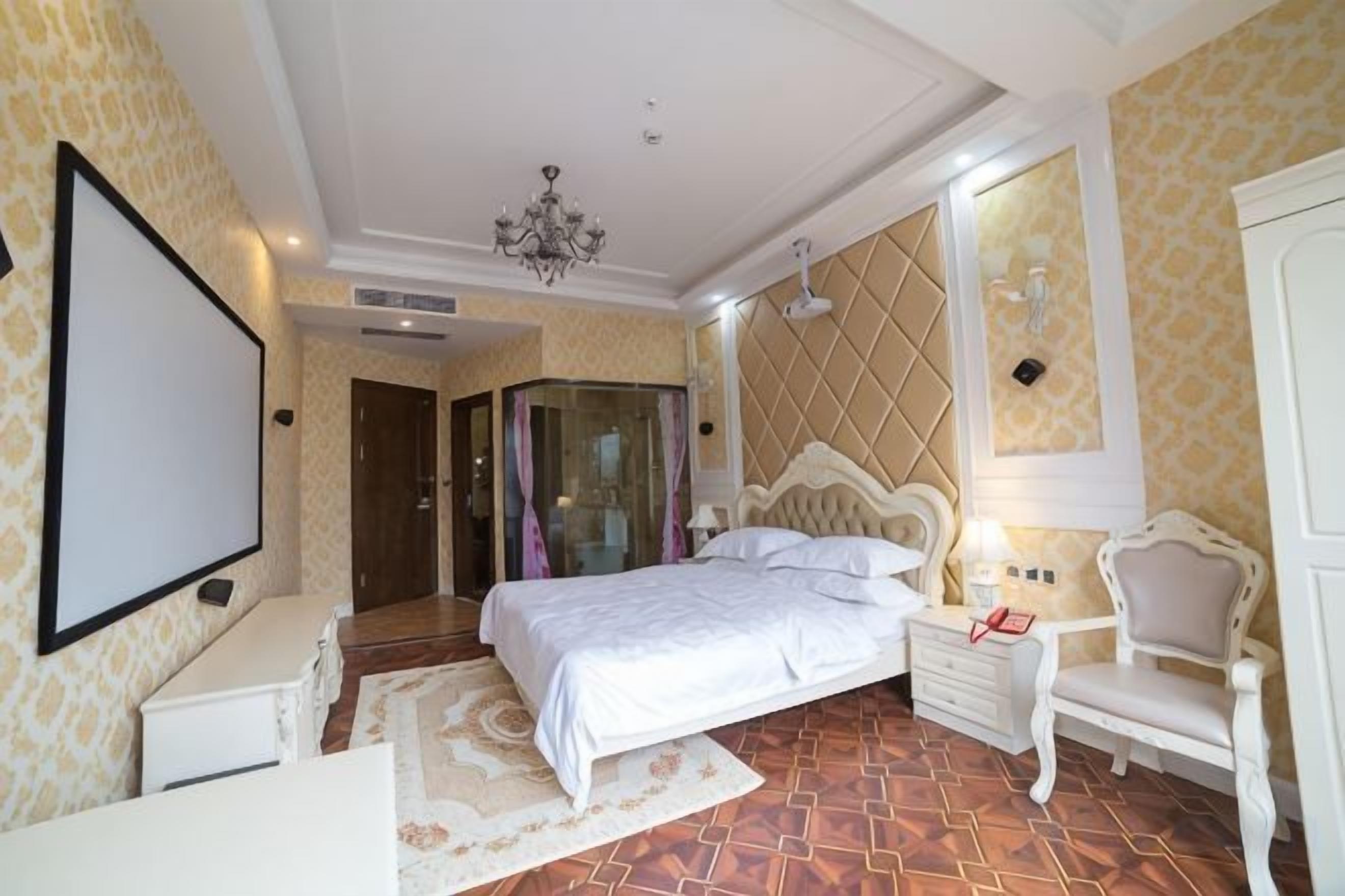 Un dormitorio con una cama grande, una mesita de noche, una silla y un televisor.