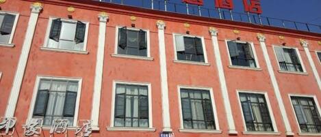 A hotel with a red facade, multiple windows, and a sign indicating a hotel and coffee shop.