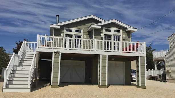 A two-story house with a balcony, a garage, and a staircase leading to the entrance. - Beautiful Raised Ranch with Views of the Bay (Surf City)
