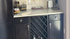 A kitchen with dark cabinets, a wine rack, and a tiled backsplash. - Beautiful Raised Ranch with Views of the Bay (Surf City)