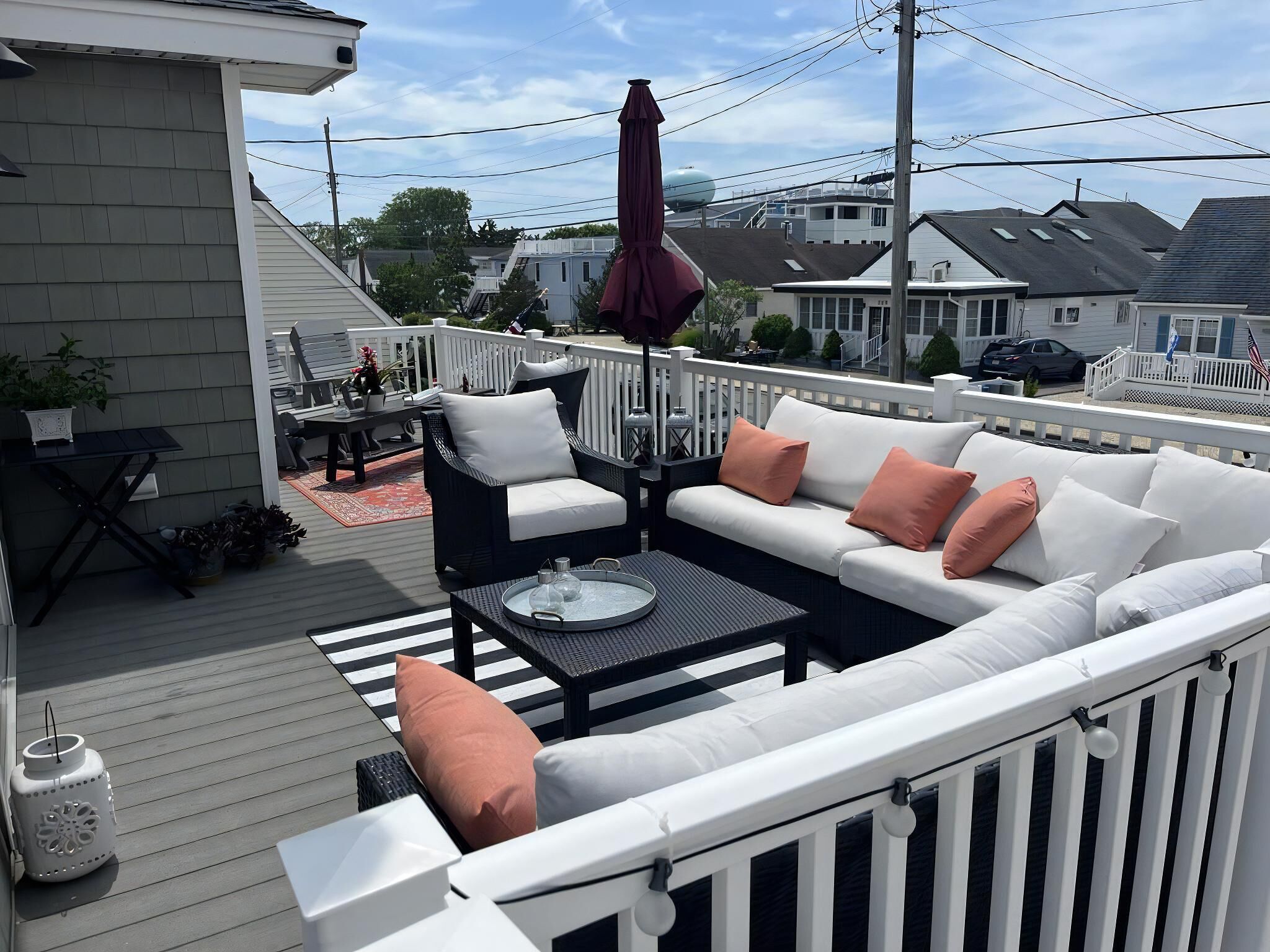 Une terrasse avec un canapé blanc, un fauteuil noir et une petite table.